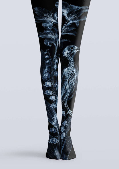 Avaeri black high-stretch tights featuring a blue X-ray style print of bird skeletons and lily-of-the-valley flowers, showcasing an avant-garde Gothic aesthetic.